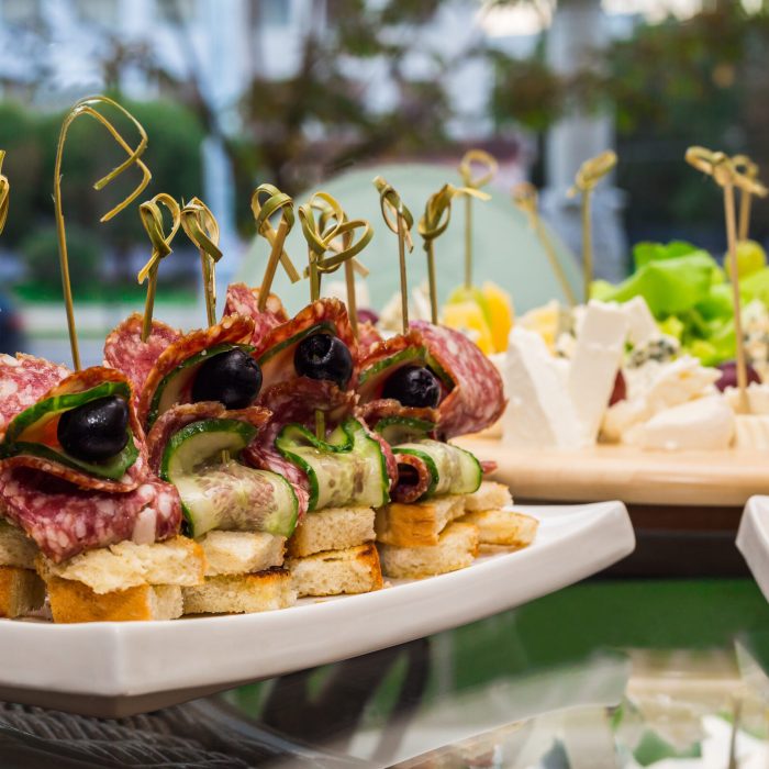 snacks assorted canapes with smoked sausage baked bread and olives with cucumber, close-up
