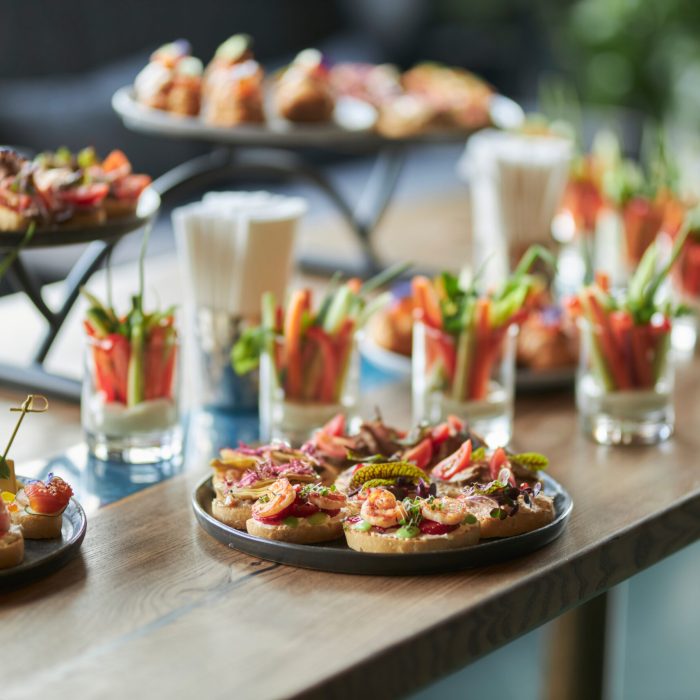 Lots of good food on the table. Small sandwiches on a black plat